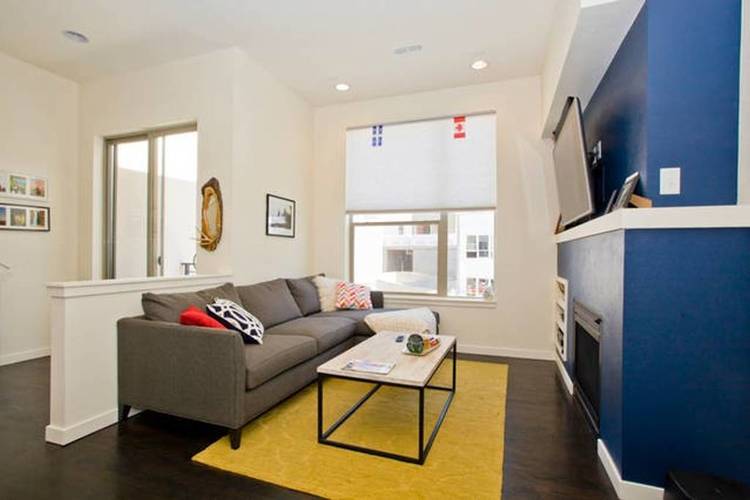 A living room with a grey couch and a yellow rug.
