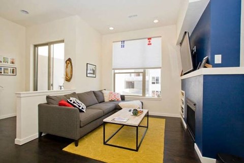 A living room with a grey couch and a yellow rug.