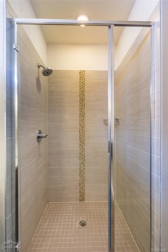 A shower with a gold shower head.
