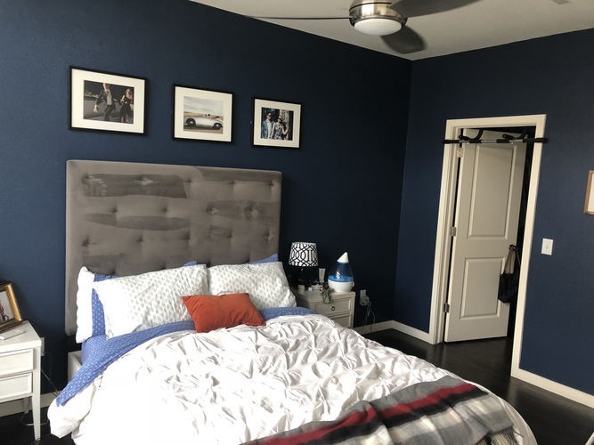 A bedroom with a bed, nightstand, and pictures on the wall.