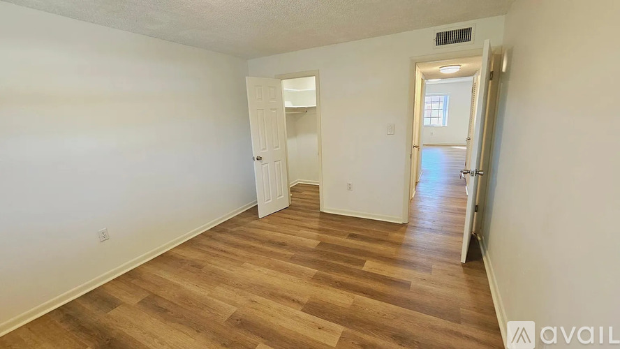 A room with wooden flooring and white walls, with a doorway leading to another room.