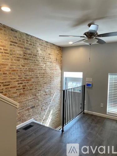 A room with a brick wall and a ceiling fan.