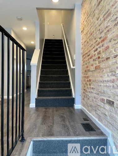A staircase with a brick wall on one side and a metal railing on the other.