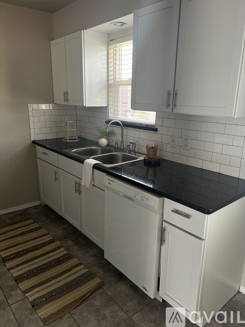 A kitchen with white cabinets and black countertops.