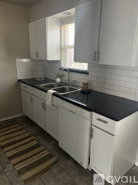 A kitchen with white cabinets and black countertops.