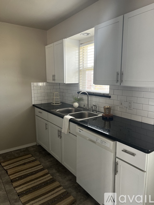 A kitchen with white cabinets and a black countertop.