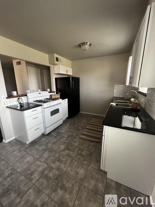 A kitchen with white appliances and black countertops.