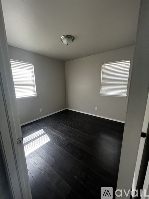 A room with a wooden floor and a window with blinds.