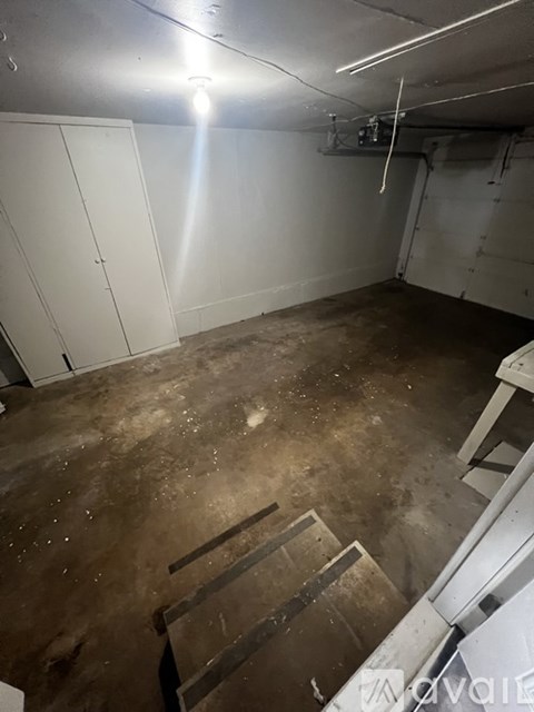 A dirty basement with a ladder and a cabinet.