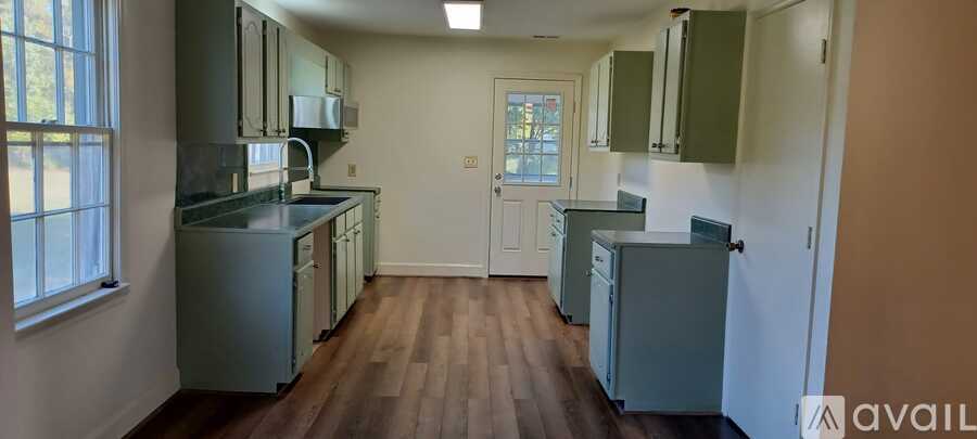 A kitchen with wooden floors and green cabinets.