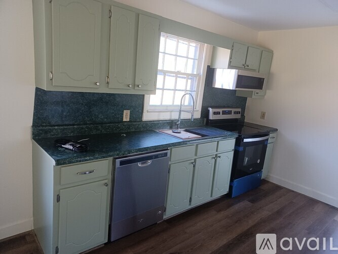 A kitchen with green cabinets and a black counter top.