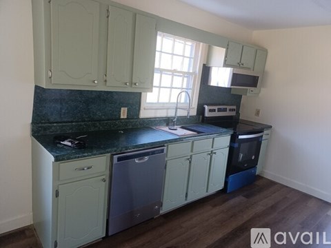 A kitchen with green cabinets and a black counter top.