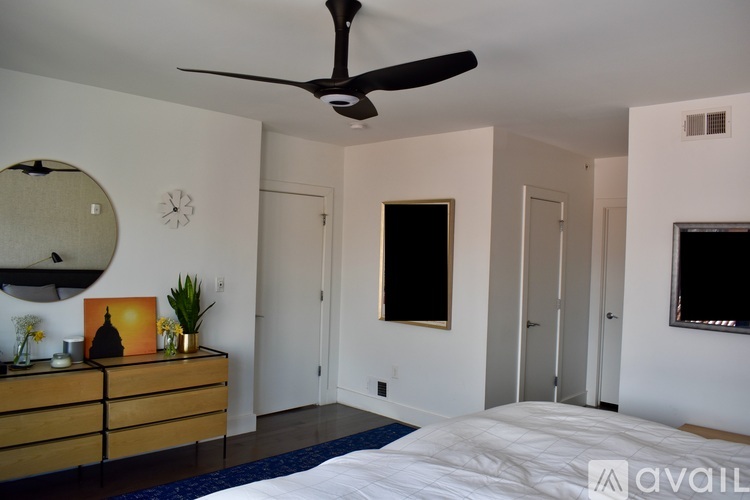 A bedroom with a ceiling fan and a bed in the corner.