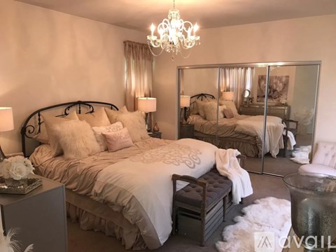 A bedroom with a large bed and a chandelier.