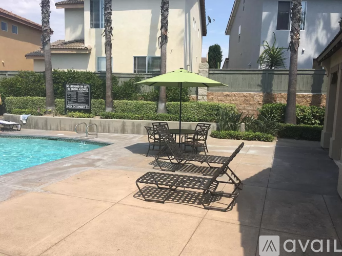 A poolside table and chairs with a green umbrella.