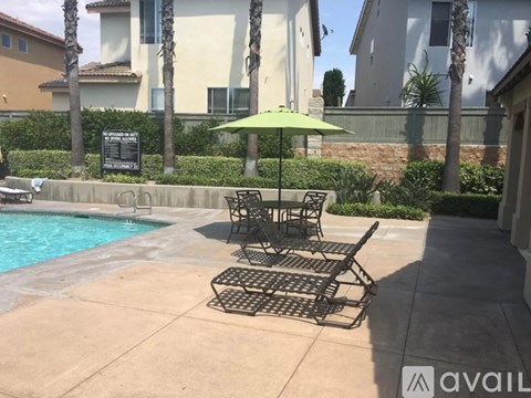 A poolside table and chairs with a green umbrella.