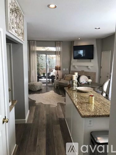 A living room with a television and a kitchen area in the background.