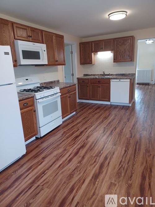 A kitchen with wooden floors and white appliances.