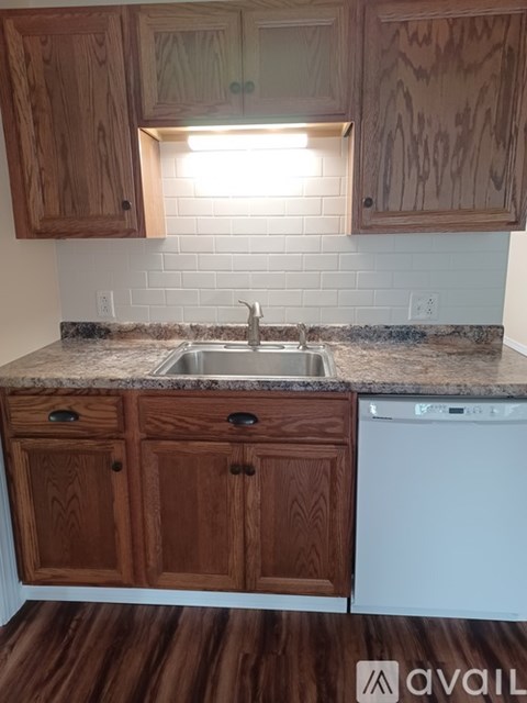 A kitchen with wooden cabinets and a white dishwasher.