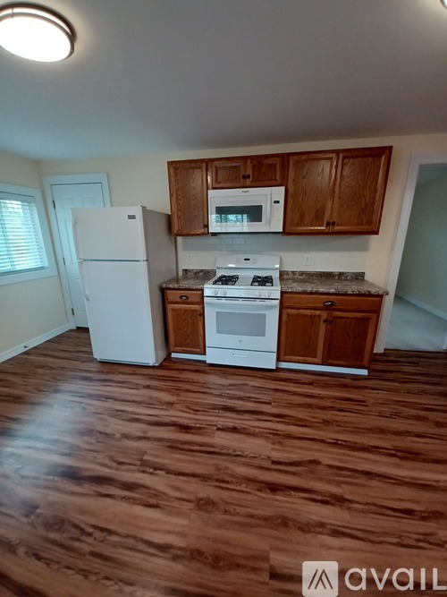 A kitchen with a white fridge, white stove, and wooden cabinets.