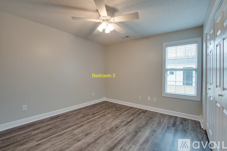 A spacious bedroom with a window and wooden flooring.