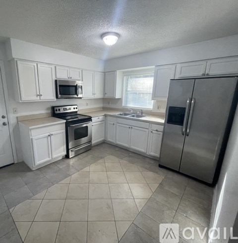 A kitchen with white cabinets and a stainless steel refrigerator.