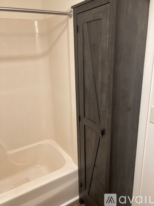 A white bathtub sits next to a wooden medicine cabinet.