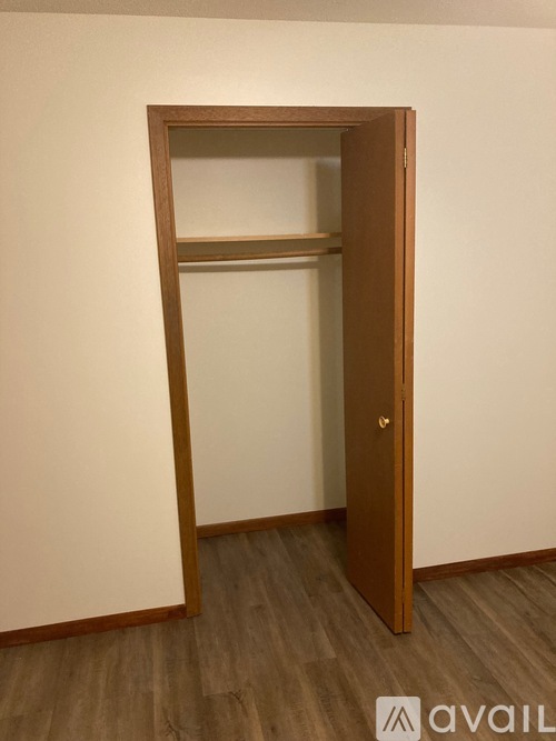 A wooden door with a shelf above it in a room with wooden flooring.