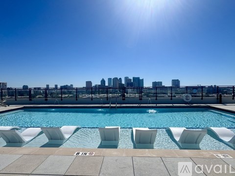 A pool with white chairs and a city skyline in the background.