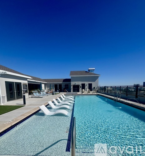 A pool with chairs and a building in the background.