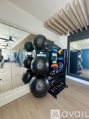 A gym room with a mirror, exercise balls, and a fan.