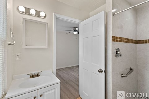 A white bathroom with a sink, mirror, and shower.