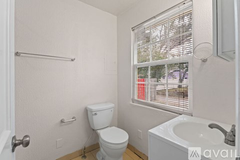 A white bathroom with a toilet, sink, and window.