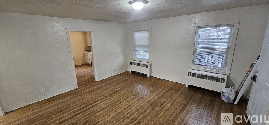 A room with wooden floors and white walls is available for rent.