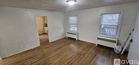 A room with wooden floors and white walls is available for rent.
