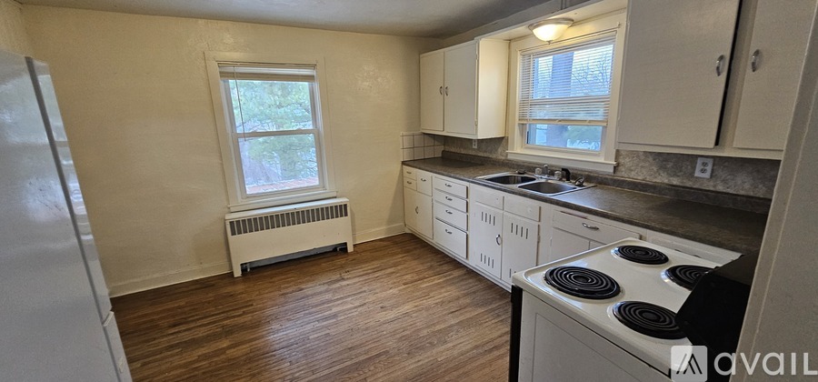 A kitchen with white appliances and wooden floors.