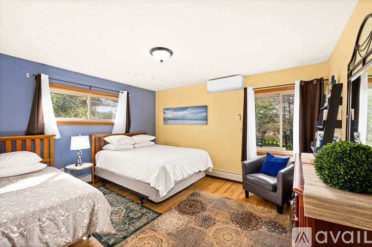 A bedroom with two beds and a chair.