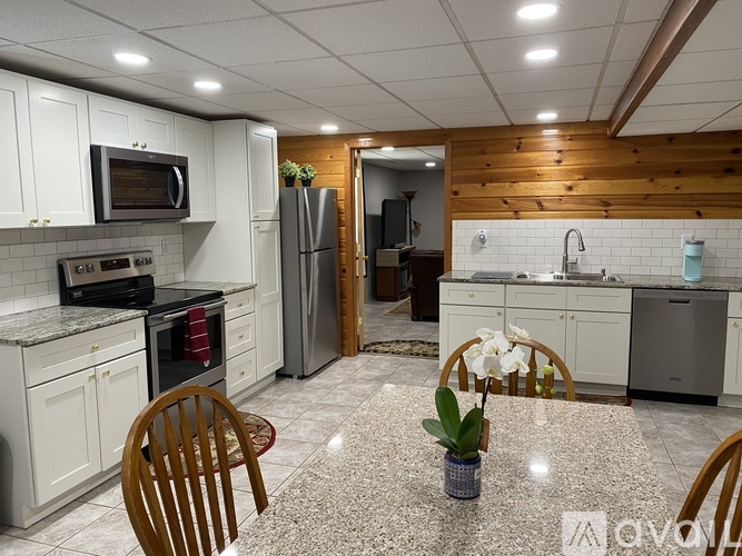 A kitchen with a granite countertop and wooden chairs.