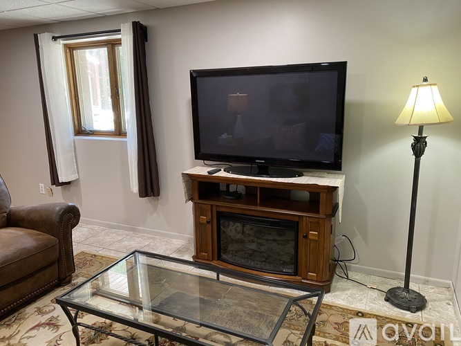A living room with a television, a glass coffee table, and a lamp.