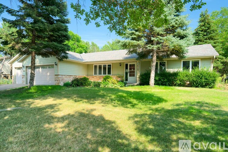 A house with a green lawn and trees in the background.