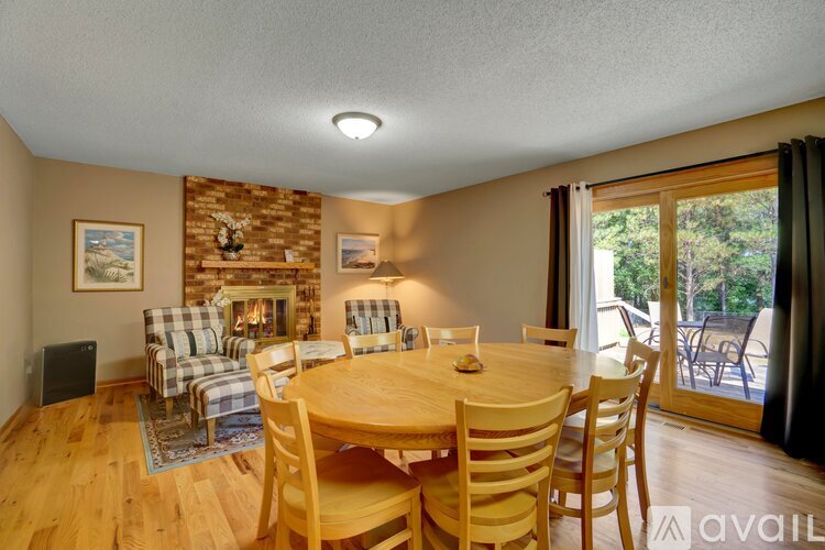 A dining room with a wooden table and chairs, a fireplace, and a painting on the wall.