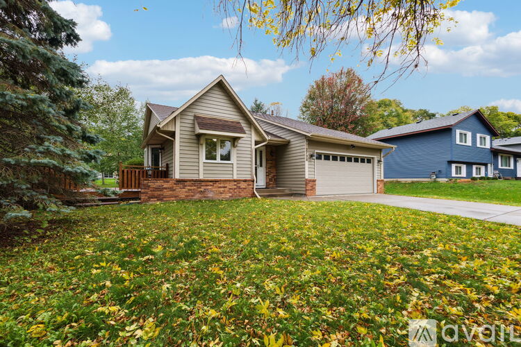 A house with a brown roof and a garage is surrounded by a grassy area with yellow flowers.