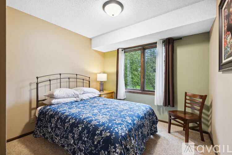 A bedroom with a bed, chair, and window.