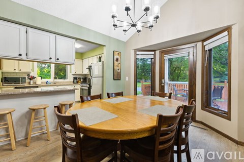 A kitchen with a table and chairs in the foreground and a window showing a backyard in the background.