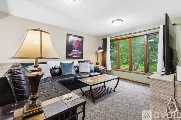 A living room with a leather couch, a coffee table, and a lamp.