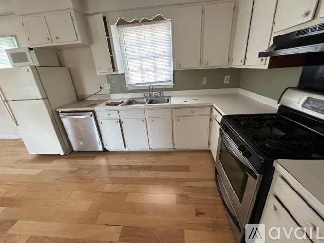 A kitchen with white appliances and wooden floors.