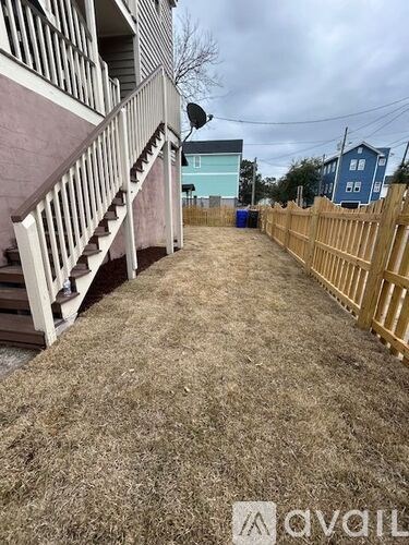 A backyard with a wooden fence and a staircase leading to a house.