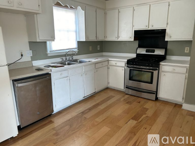 A kitchen with white cabinets and a wooden floor.
