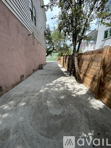 A narrow alley with a wooden fence on one side and a pink building on the other.