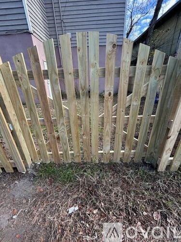 A wooden fence is in front of a house.